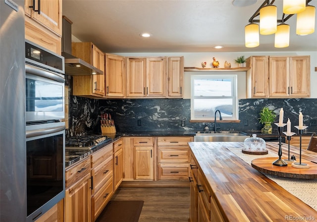 kitchen featuring dark wood finished floors, appliances with stainless steel finishes, light brown cabinets, a sink, and wood counters