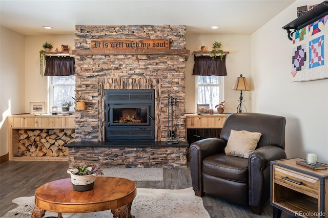 living area featuring recessed lighting, a stone fireplace, and wood finished floors