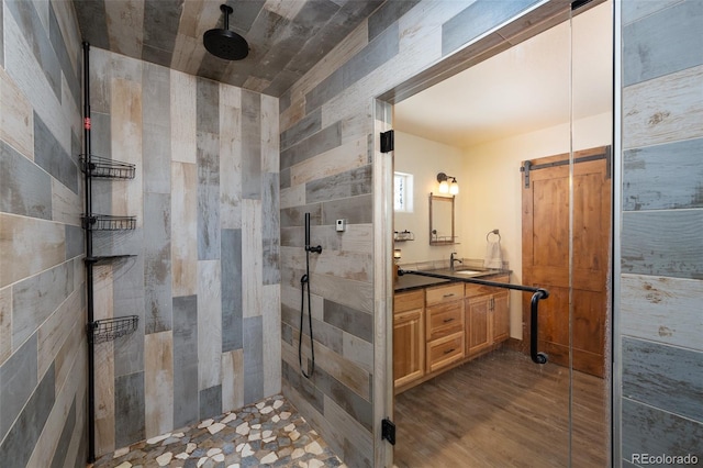 bathroom with a tile shower, wood finished floors, and vanity