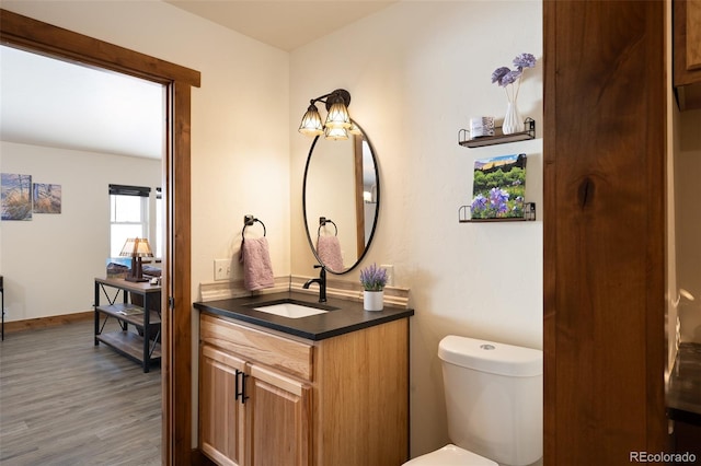 bathroom with toilet, baseboards, wood finished floors, and vanity