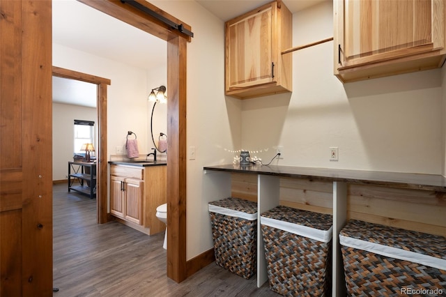 interior space with a barn door, light brown cabinets, dark wood-style flooring, baseboards, and dark countertops