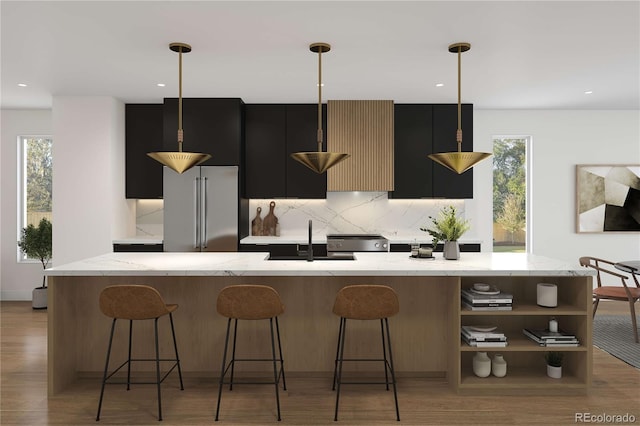 kitchen featuring light wood-style flooring, a sink, decorative backsplash, high end refrigerator, and dark cabinets