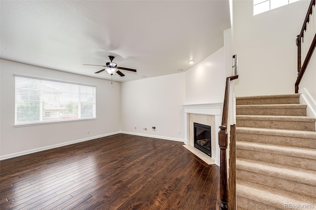 6528 S Kewaunee Way, Aurora, CO 80016 - unfurnished living room with stairs, a ceiling fan, dark wood-style floors, and a fireplace