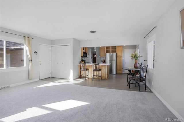 carpeted living area featuring baseboards and visible vents