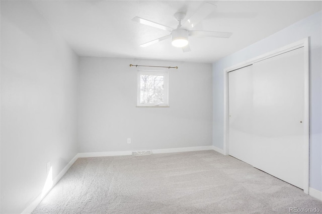 unfurnished bedroom with a closet, carpet flooring, ceiling fan, and baseboards