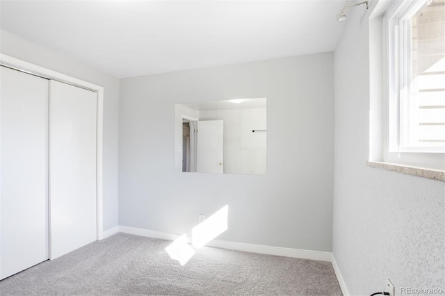 unfurnished bedroom with carpet, a closet, and baseboards