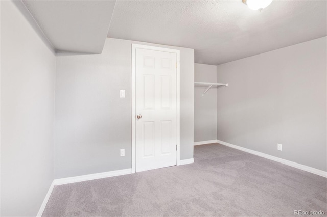 unfurnished bedroom with a textured ceiling, a closet, carpet flooring, and baseboards