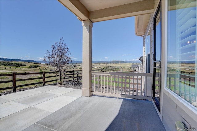 view of patio / terrace with a rural view, a mountain view, and a balcony