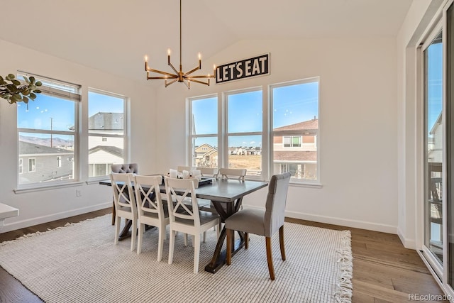 dining area with vaulted ceiling, wood-type flooring, and an inviting chandelier