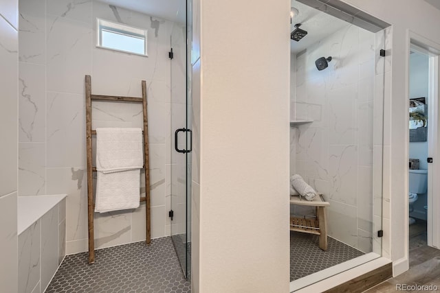 bathroom featuring a shower with shower door and toilet