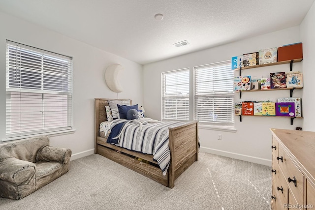 bedroom featuring light carpet and a textured ceiling