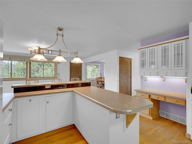 5336 High Rd, Evergreen, CO 80439 - kitchen with white cabinets, light wood finished floors, glass insert cabinets, light countertops, and pendant lighting
