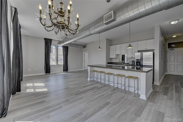 kitchen with stainless steel appliances, a notable chandelier, decorative light fixtures, a breakfast bar area, and white cabinets