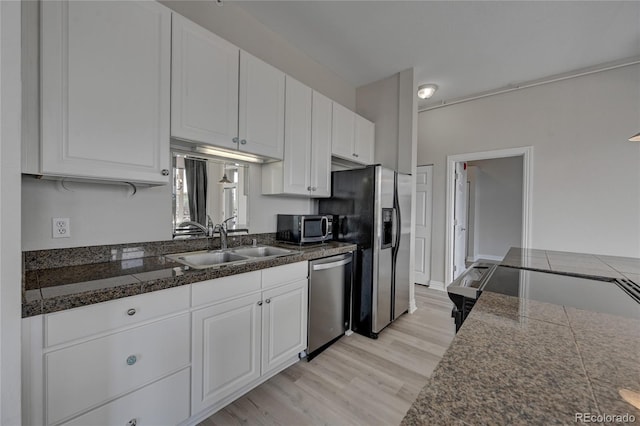 kitchen with stainless steel appliances, tile counters, light wood-style flooring, white cabinetry, and a sink