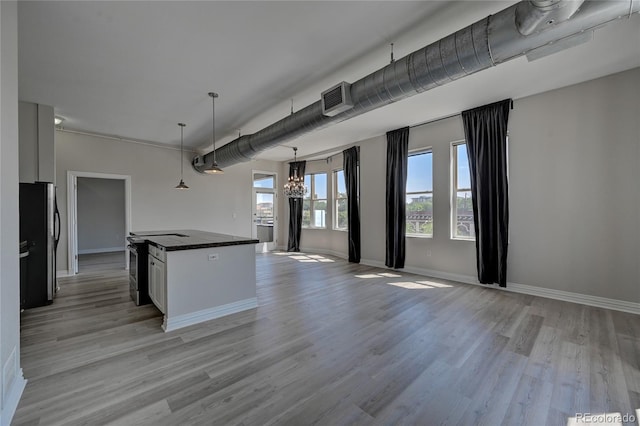 kitchen featuring freestanding refrigerator, hanging light fixtures, an inviting chandelier, stainless steel electric stove, and white cabinetry