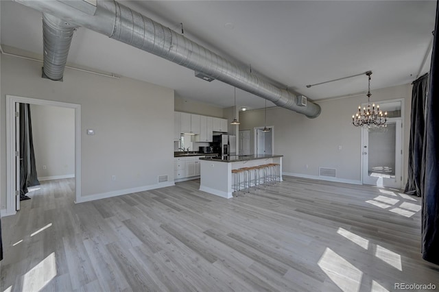 unfurnished living room with light hardwood / wood-style floors, an inviting chandelier, and sink