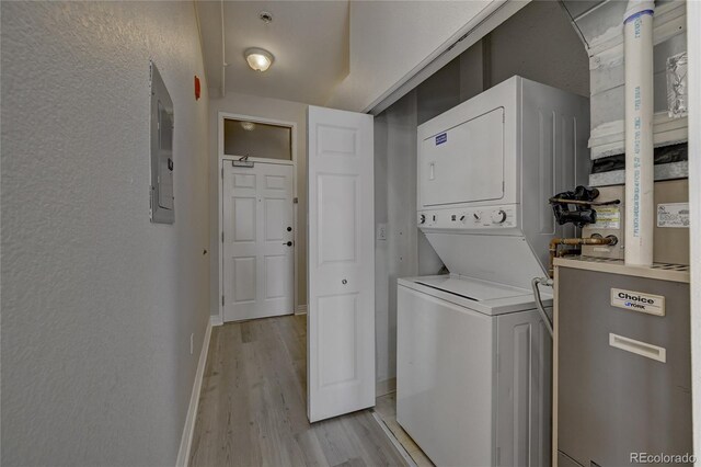 laundry room featuring light wood-type flooring, stacked washer and dryer, and electric panel