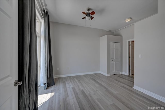 unfurnished room with a ceiling fan, light wood-type flooring, and baseboards