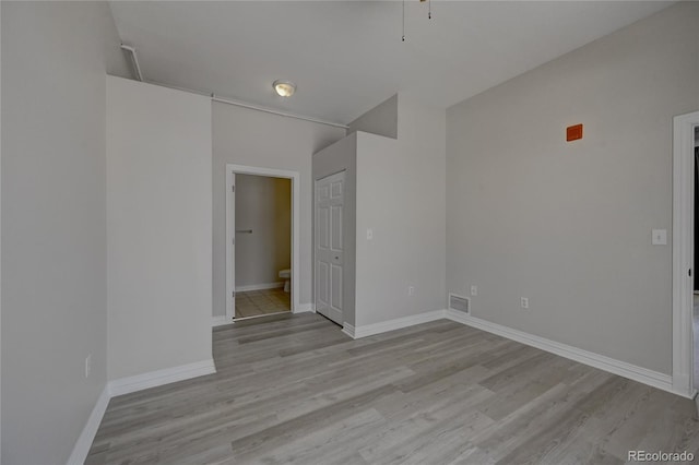 empty room with light wood-type flooring, visible vents, and baseboards