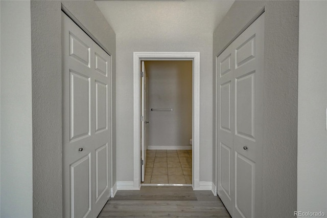 hallway featuring light wood-type flooring and baseboards