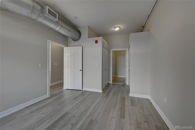 unfurnished room featuring light wood-type flooring, visible vents, and baseboards