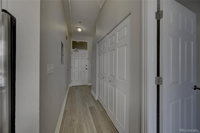 corridor with light wood-style flooring and baseboards