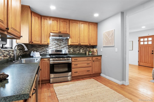 10563 Pierson Cir, Broomfield, CO 80021 - kitchen with stainless steel gas range oven, under cabinet range hood, tasteful backsplash, light wood-style floors, and dark countertops