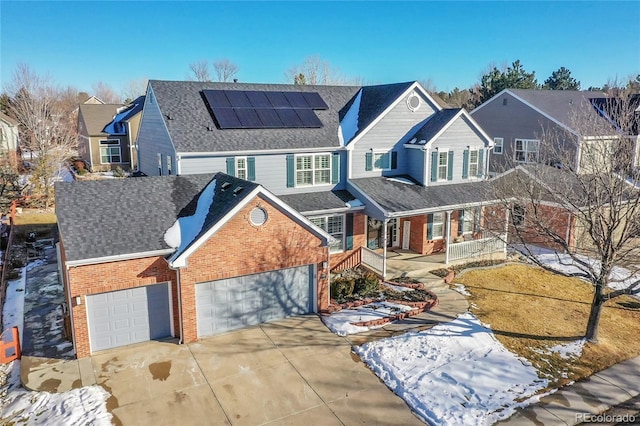 view of front facade with a garage, solar panels, and covered porch