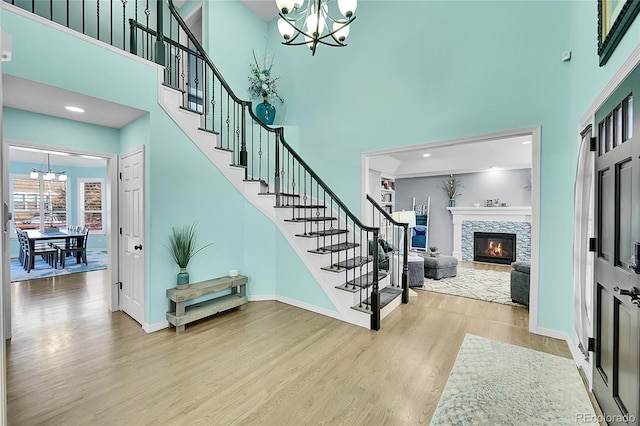 stairway featuring an inviting chandelier, wood-type flooring, and a high ceiling