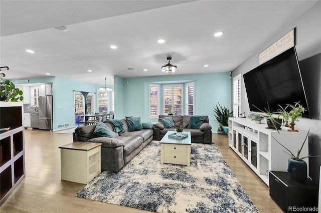 living room featuring a chandelier, sink, and light wood-type flooring