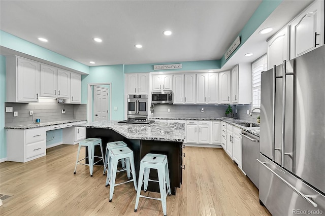 kitchen with a kitchen breakfast bar, appliances with stainless steel finishes, white cabinets, and a kitchen island