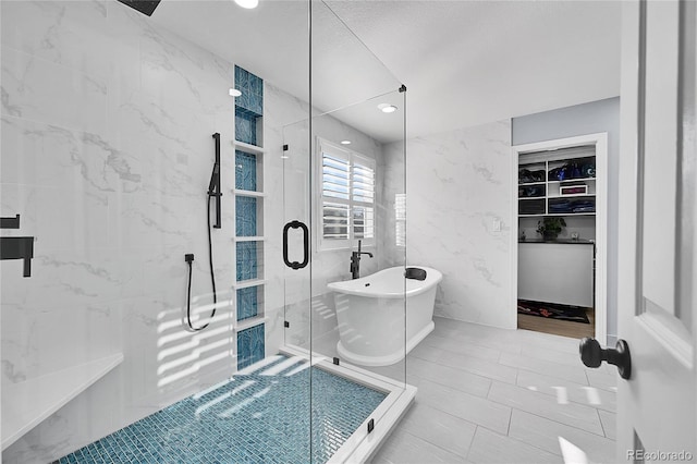 bathroom with separate shower and tub, tile patterned flooring, and tile walls