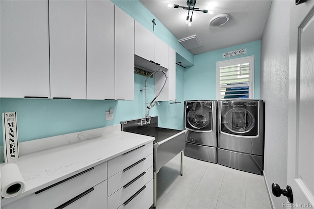 laundry room featuring cabinets, washer and dryer, and a textured ceiling