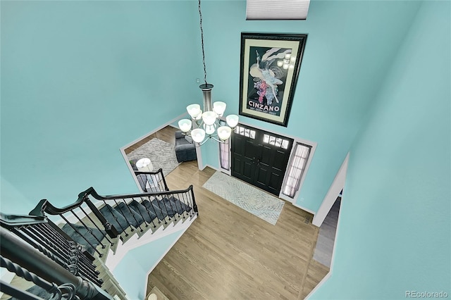 foyer entrance with hardwood / wood-style flooring, a high ceiling, and a notable chandelier