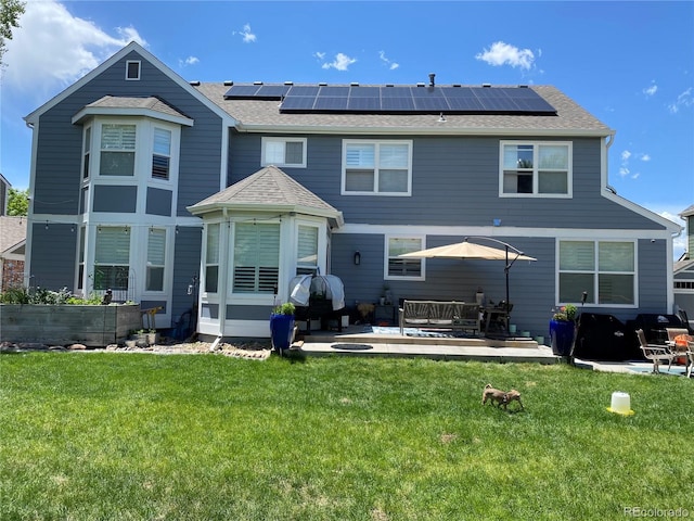 back of house featuring a lawn, an outdoor hangout area, a patio area, and solar panels