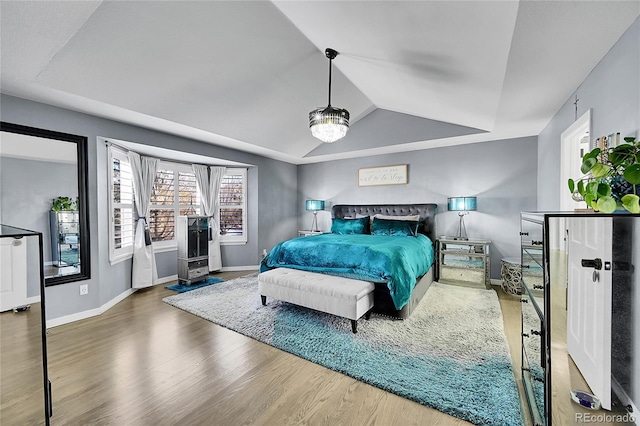 bedroom featuring a raised ceiling, vaulted ceiling, and hardwood / wood-style flooring