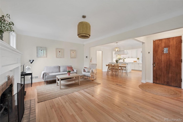 770 Locust, Denver, CO 80220 - living room with a fireplace, light wood-style flooring, and baseboards