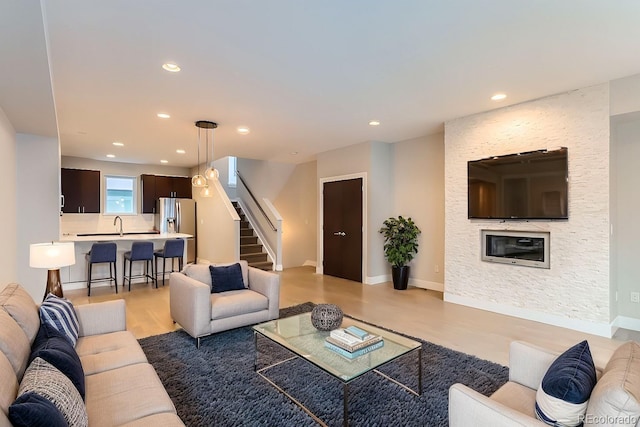 living room featuring a stone fireplace and light hardwood / wood-style floors