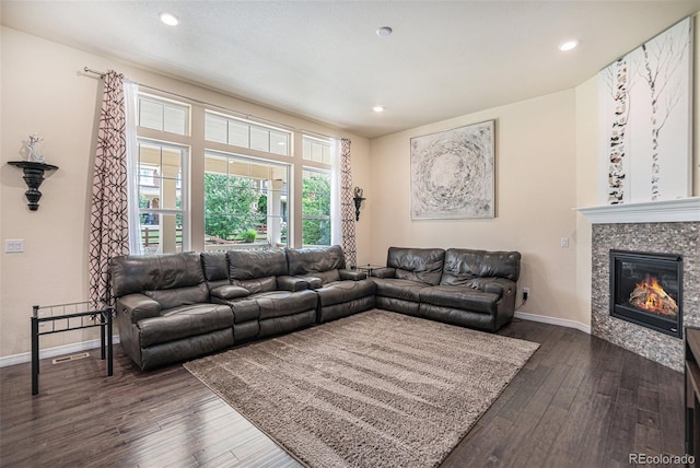 living area with a glass covered fireplace, dark wood-style flooring, baseboards, and recessed lighting