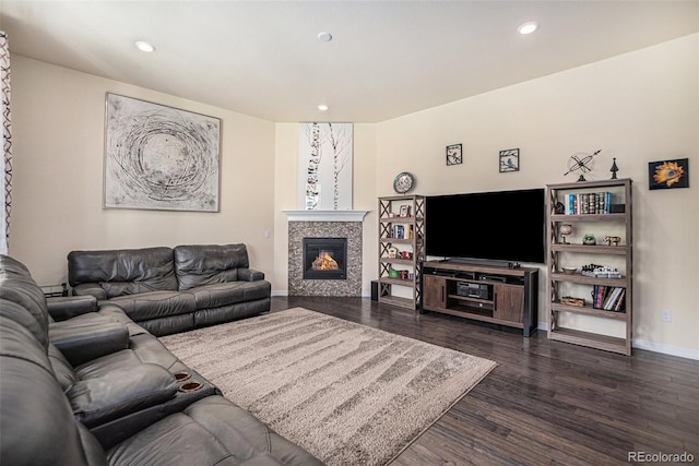 living room with baseboards, dark wood-type flooring, a tiled fireplace, and recessed lighting