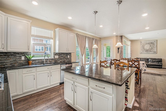 kitchen with white cabinets, dishwasher, open floor plan, decorative light fixtures, and a sink