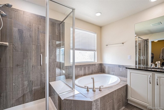 bathroom with a garden tub, a shower stall, visible vents, and vanity