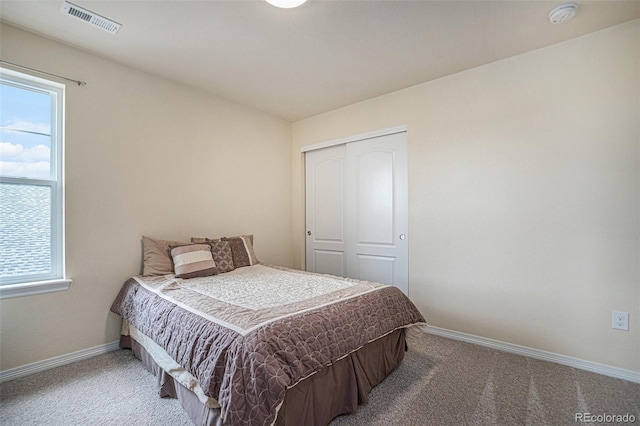 carpeted bedroom featuring a closet, visible vents, and baseboards