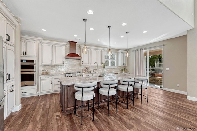 kitchen featuring a breakfast bar, dark wood finished floors, custom exhaust hood, backsplash, and stainless steel double oven