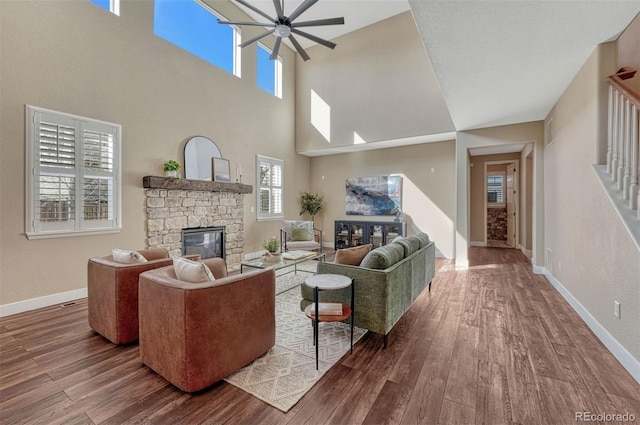 living area with stairs, baseboards, wood finished floors, and a stone fireplace