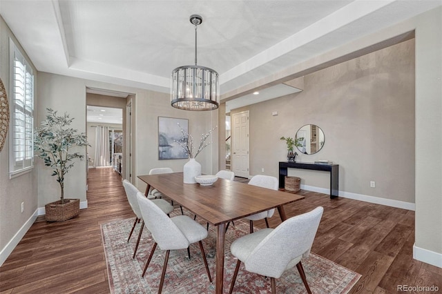 dining area with dark wood-style floors, baseboards, and a tray ceiling