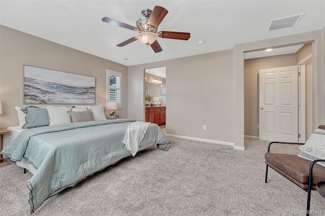 bedroom featuring light colored carpet, visible vents, a ceiling fan, ensuite bath, and baseboards