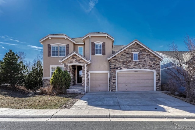 traditional-style home featuring a garage, stone siding, concrete driveway, and stucco siding