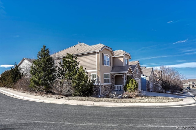 view of front of property with stone siding, a tiled roof, and stucco siding