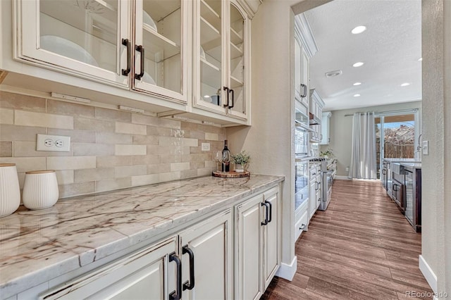 10761 Hillsboro Cir, Parker, CO 80134 - kitchen featuring dark wood-style floors, backsplash, recessed lighting, glass insert cabinets, and white cabinetry
